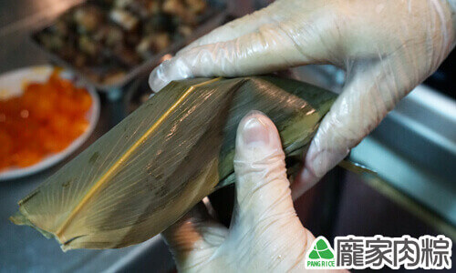右手將剩餘的粽葉蓋回將粽子包覆