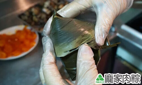 將收在一起的粽葉，順著肉粽往左或右折(沒有一定要往左或右，只要粽葉好折、繩子好綁就可以)