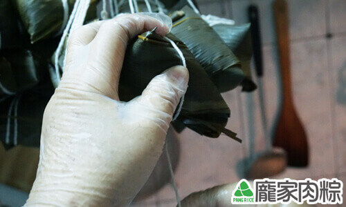 用粽繩繞粽子兩圈扎緊固定