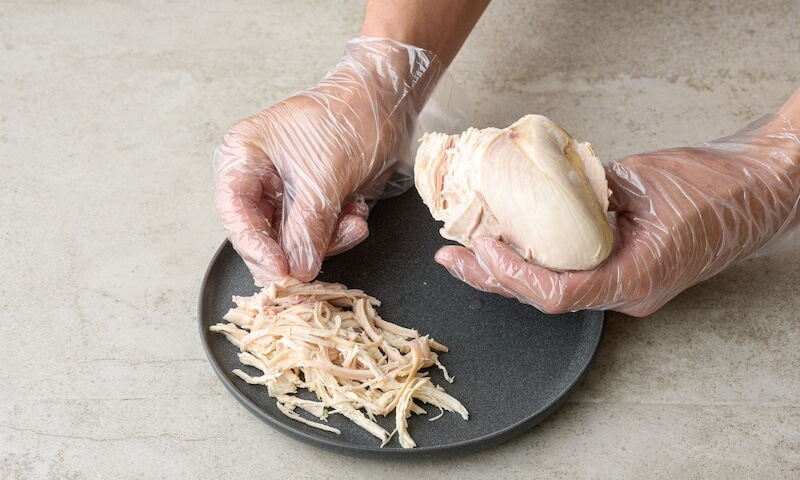 以人工費時費力將雞肉撕成適合的大小，保留有機雞肉口感、完美入味